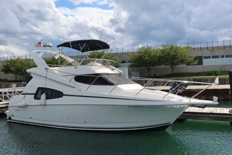 The Image of 2000 Silverton 330 Sport Bridge yacht docked at marina under cloudy sky. - 3