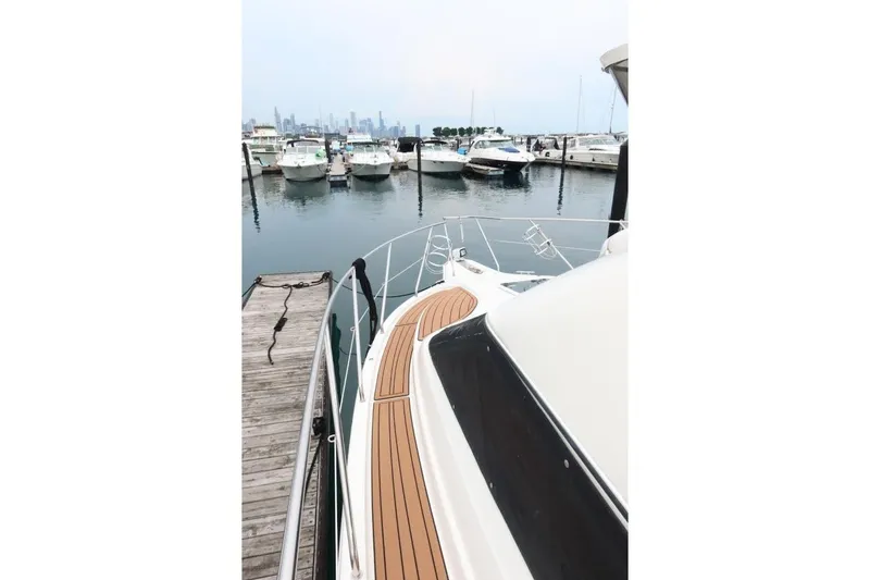 Slide: The Image of 2000 Silverton 330 Sport Bridge yacht docked at marina with city skyline view. - 22