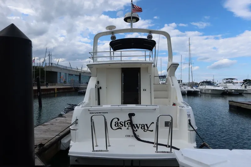 Slide: The Image of 2000 Silverton 330 Sport Bridge yacht docked at marina under cloudy sky. - 7