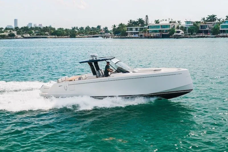 Slide: The Image of 2021 Pardo Yachts P38 cruising on turquoise water near modern waterfront homes. - 16