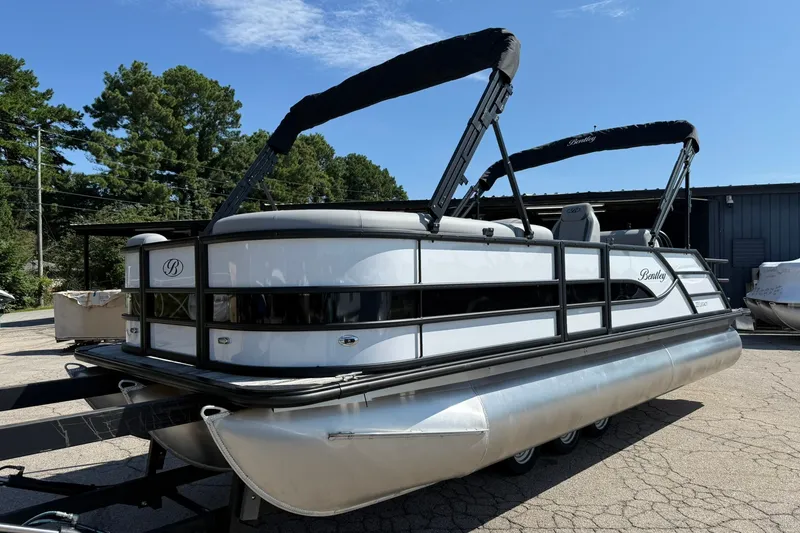 Slide: The Image of 2026 Bentley Pontoons Legacy 223 Swingback on trailer, parked outdoors under clear sky. - 1