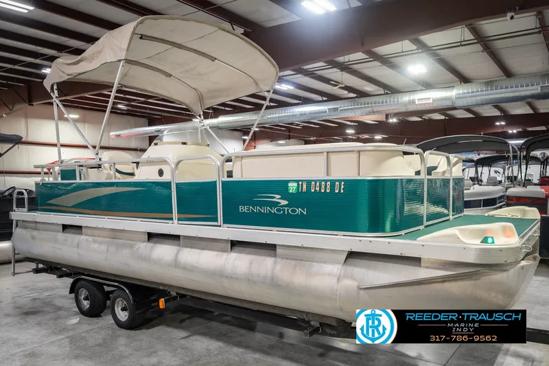 Slide: The Image of 2000 Bennington 227L pontoon boat with canopy, displayed indoors on a trailer. - 5