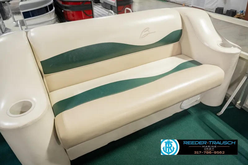 Slide: The Image of Bennington 227L 2000 boat seat with green accents and cup holders in showroom. - 43