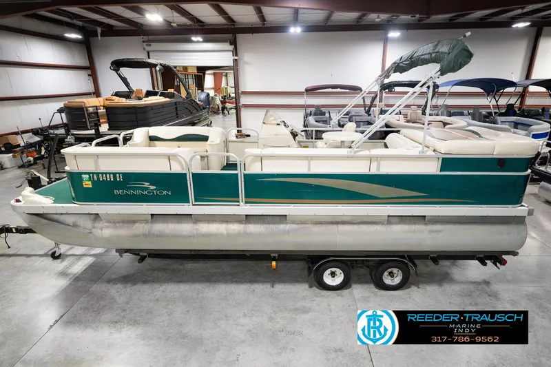 The Image of 2000 Bennington 227L pontoon boat in a showroom, featuring green and white design. - 0