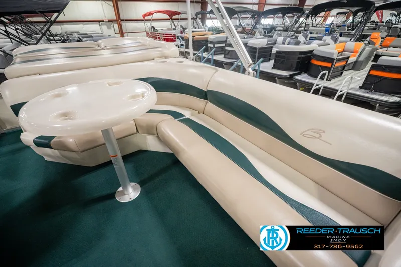 Slide: The Image of Bennington 227L 2000 pontoon boat interior with seating and table in showroom. - 28