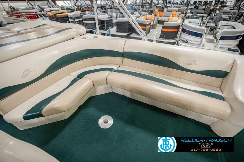 Slide: The Image of 2000 Bennington 227L boat interior with beige and green seating in showroom. - 44