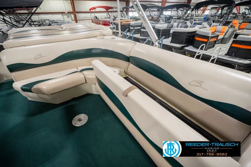Slide: The Image of 2000 Bennington 227L boat interior with beige and green seating in showroom. - 32