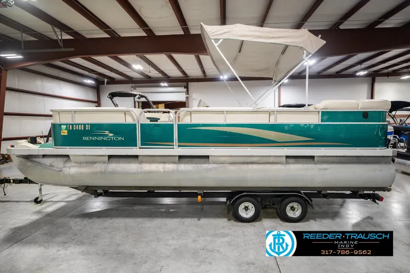 Slide: The Image of 2000 Bennington 227L pontoon boat in a warehouse, featuring teal and white design. - 12