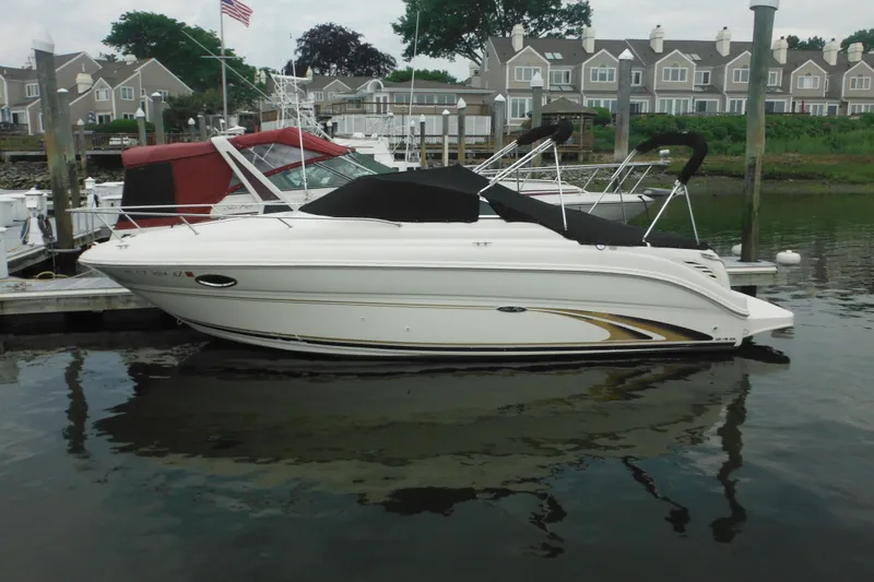 The Image of 2004 Sea Ray 245 Weekender boat docked in a marina with waterfront homes. - 0