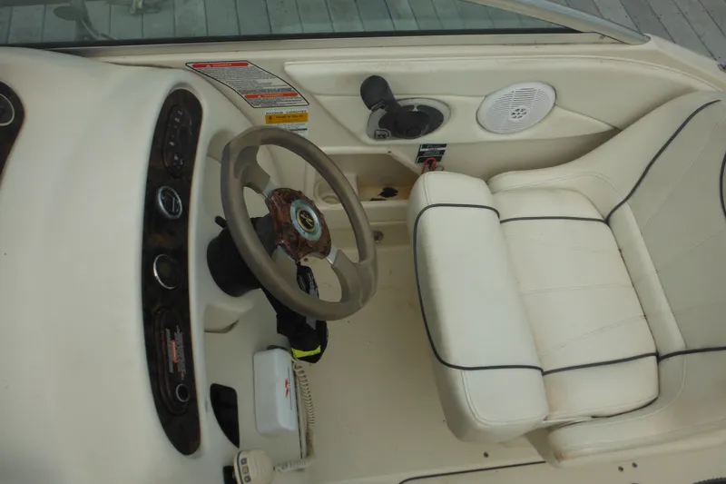 Slide: The Image of 2004 Sea Ray 245 Weekender boat interior with steering wheel and white seating. - 55