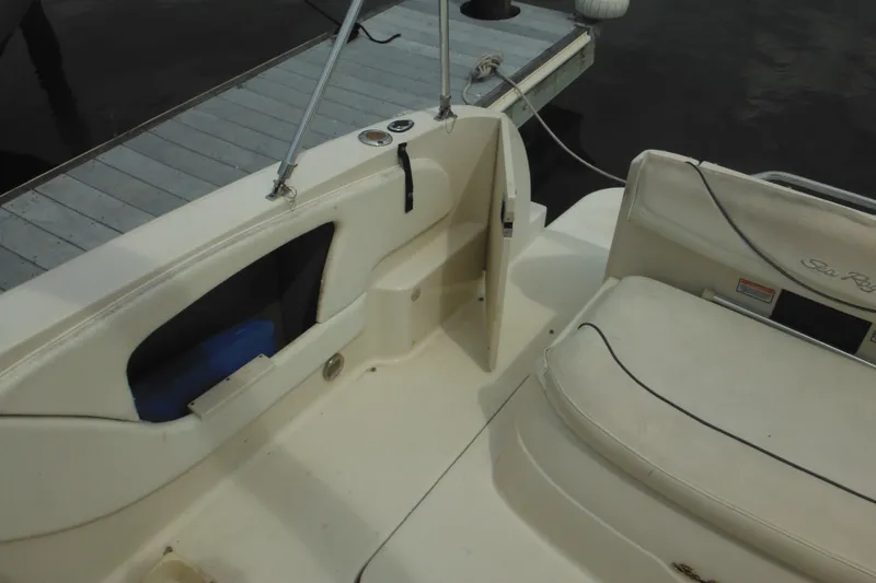 Slide: The Image of 2004 Sea Ray 245 Weekender boat interior with seating and storage, docked by the water. - 19