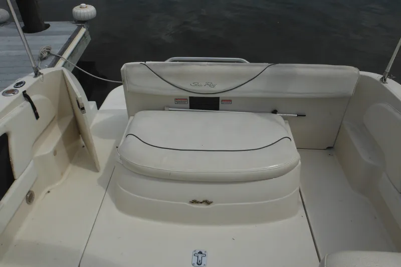 Slide: The Image of 2004 Sea Ray 245 Weekender boat interior with white seating and dock view. - 18