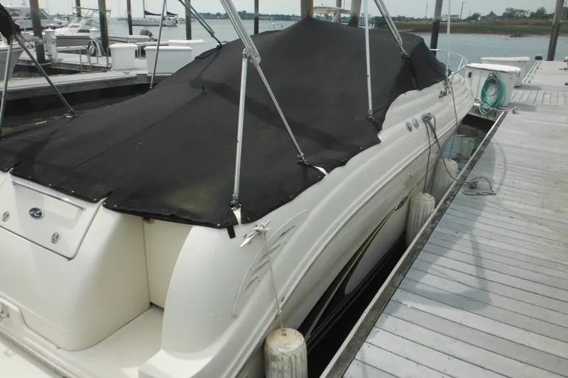 Slide: The Image of 2004 Sea Ray 245 Weekender boat docked with black cover, side view. - 16