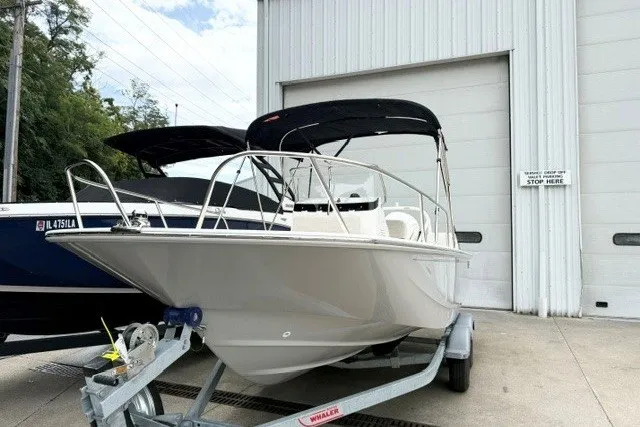 Slide: The Image of 2027 Boston Whaler 190 Montauk boat on trailer, parked outside a large garage. - 1