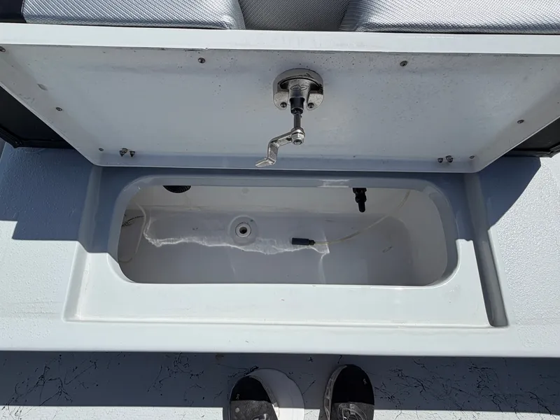 Slide: The Image of An open storage compartment on a boat with a gray interior and a metal handle. - 27