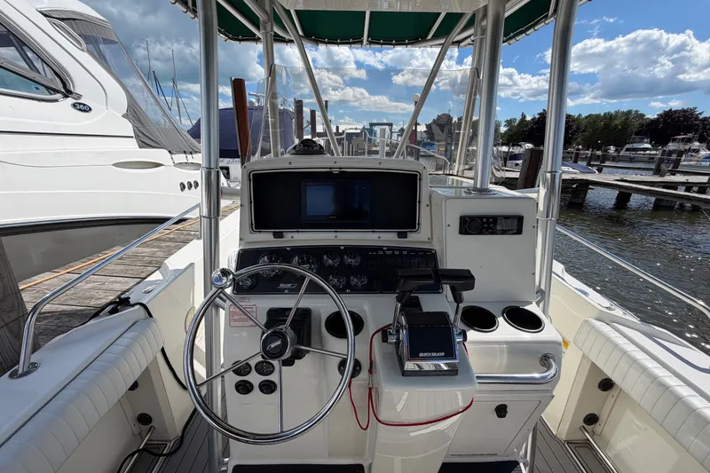 Slide: The Image of 1999 Boston Whaler 26 Outrage boat helm with steering wheel and controls at marina. - 22