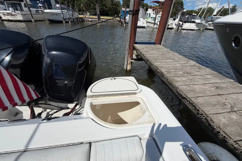Slide: The Image of 1999 Boston Whaler 26 Outrage docked, featuring dual outboard motors and an open storage compartment. - 15