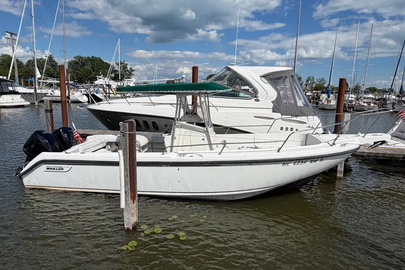 The Image of 1999 Boston Whaler 26 Outrage boat docked in a marina under a cloudy sky. - 3