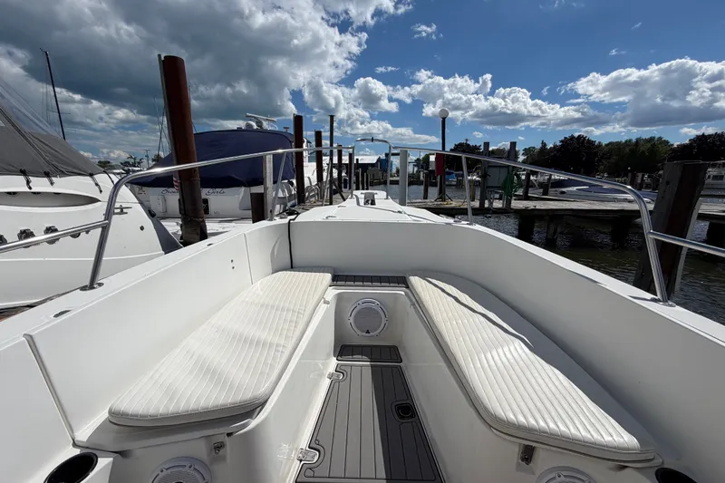 Slide: The Image of 1999 Boston Whaler 26 Outrage boat interior with cushioned seating at a marina. - 36