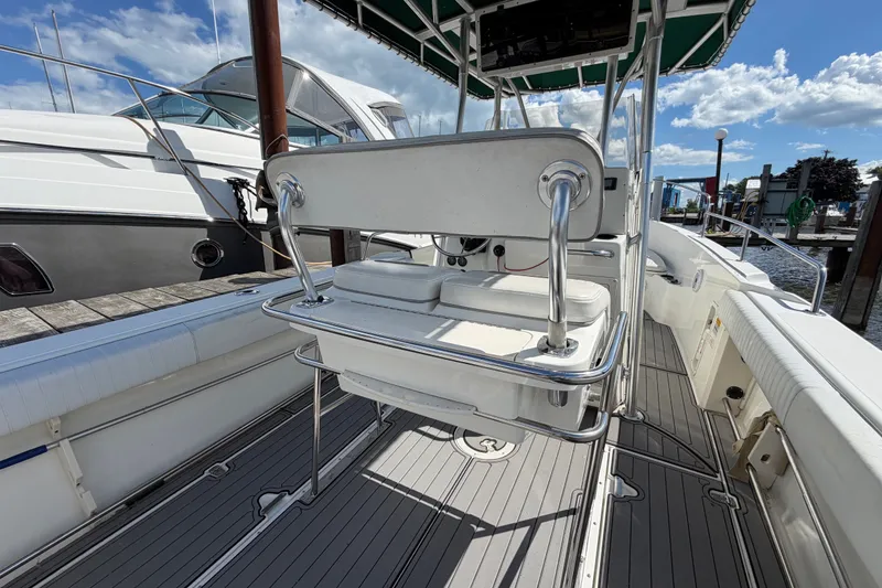 Slide: The Image of 1999 Boston Whaler 26 Outrage boat interior with seating and helm, docked under blue sky. - 17