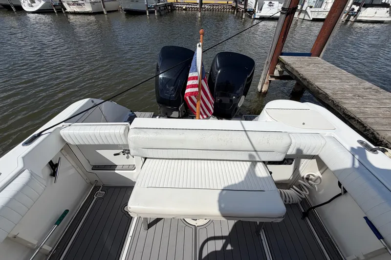 Slide: The Image of 1999 Boston Whaler 26 Outrage boat with dual engines and American flag at dock. - 13