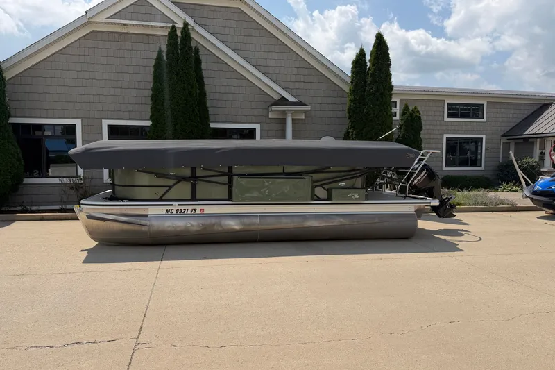 Slide: The Image of 2025 Crest Classic 200 pontoon boat parked outside a building under a cloudy sky. - 2