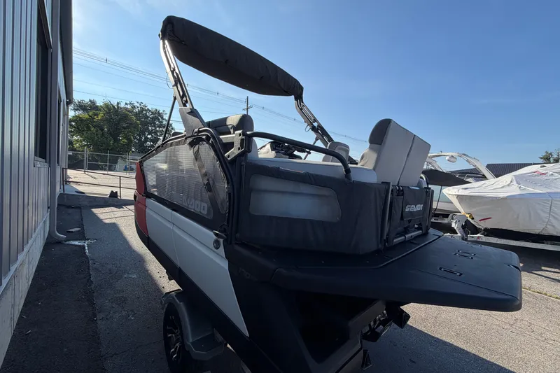 Slide: The Image of 2024 Sea-Doo Switch Compact pontoon boat parked outdoors under clear blue sky. - 12