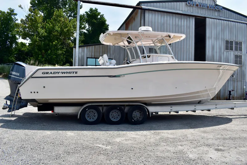 Slide: The Image of 2013 Grady-White Canyon 336 boat on trailer, parked near a metal building. - 16