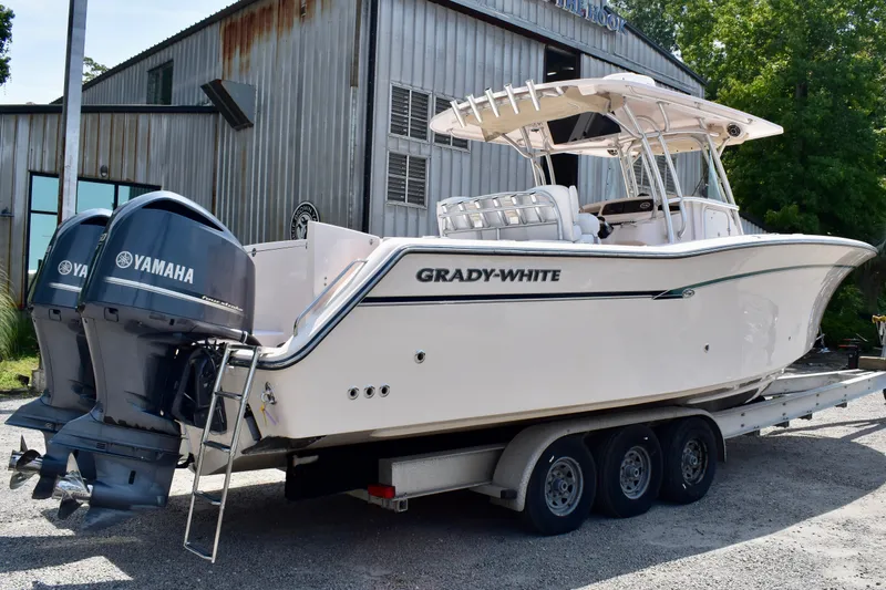 Slide: The Image of 2013 Grady-White Canyon 336 boat on trailer with Yamaha engines, parked near metal building. - 15