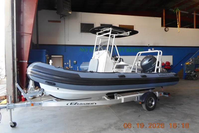 Slide: The Image of 2025 Highfield Patrol 540 boat on EZ Loader trailer in a garage setting. - 1