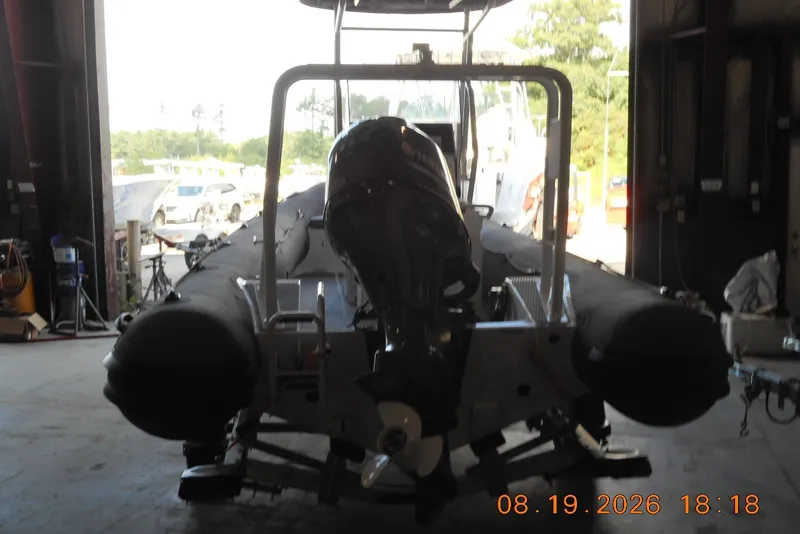 Slide: The Image of 2025 Highfield Patrol 540 boat in a garage, rear view with outboard motor. - 3
