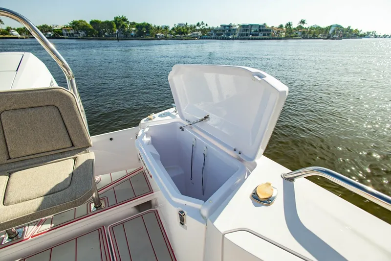 Slide: The Image of 2025 Axopar 37 Sun-Top boat with open storage compartment, scenic waterfront view. - 19
