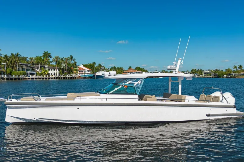 The Image of 2025 Axopar 37 Sun-Top boat cruising on a sunny day, with waterfront homes in the background. - 1