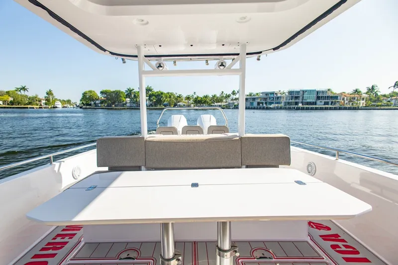Slide: The Image of 2025 Axopar 37 Sun-Top boat interior with table, overlooking serene waterfront homes. - 21
