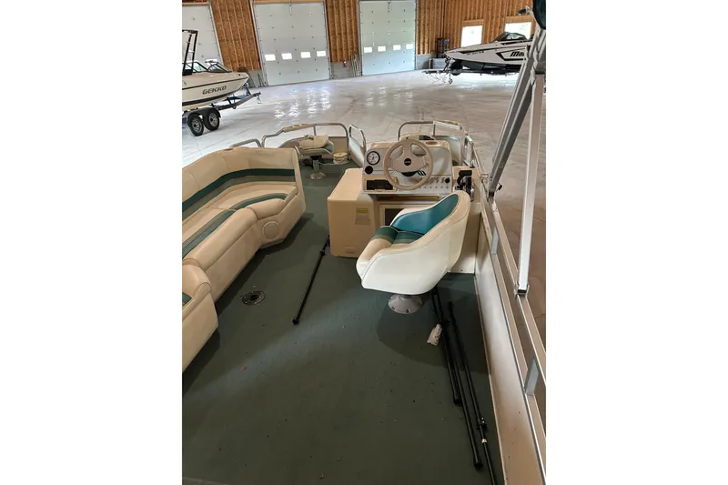 Slide: The Image of 1995 Premier 210 Cast-A-Way pontoon boat interior with seating and steering wheel in a garage. - 2