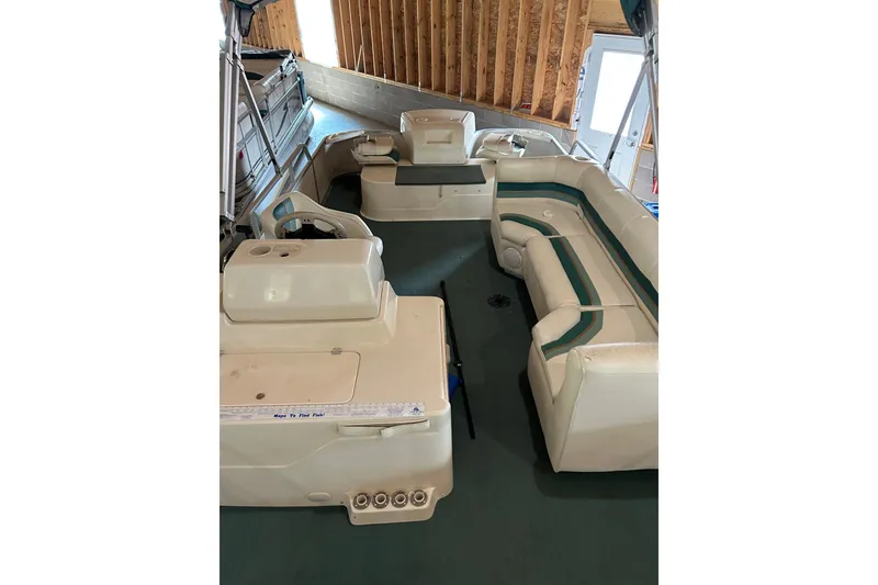 The Image of 1995 Premier 210 Cast-A-Way pontoon boat interior with seating and helm in a wooden boathouse. - 1