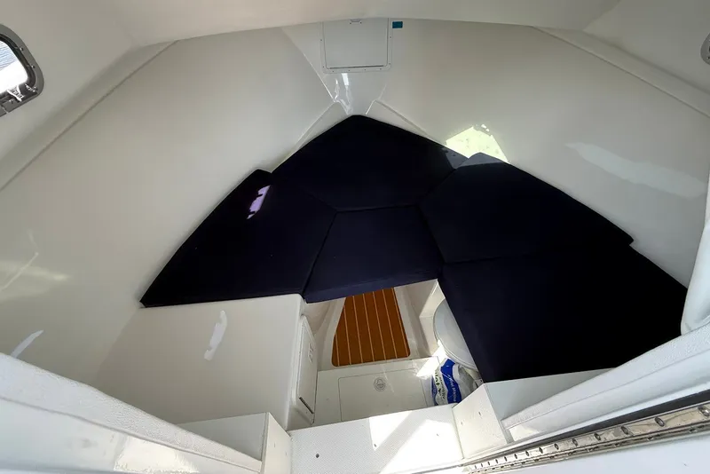 Slide: The Image of 2026 Steiger Craft 28 Annapolis cabin interior with dark cushions and wooden flooring. - 34