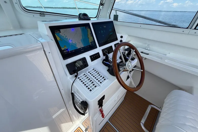 Slide: The Image of Helm of 2026 Steiger Craft 28 Annapolis with dual navigation screens and wooden steering wheel. - 29