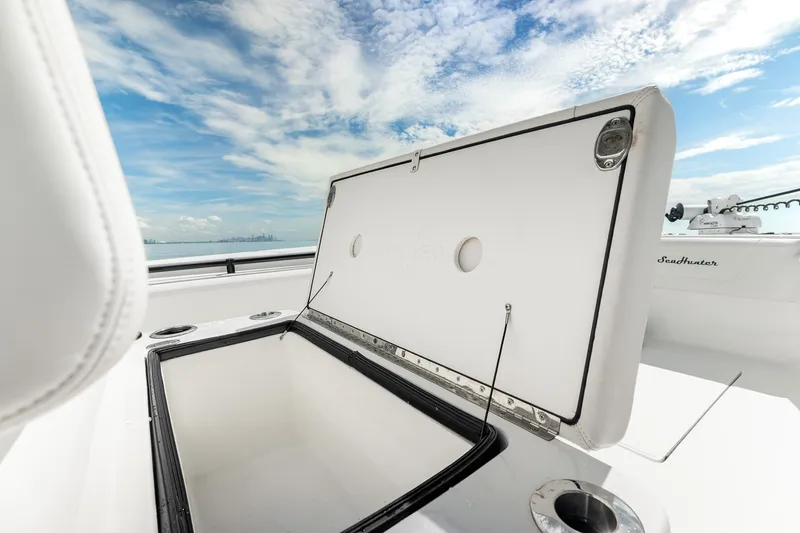 Slide: The Image of 2024 SeaHunter 28 Floridian boat with open storage compartment under a clear blue sky. - 24