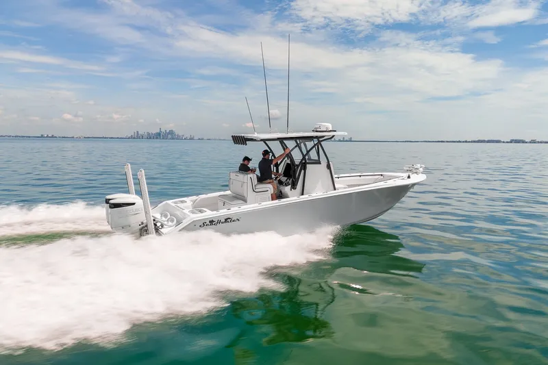 Slide: The Image of 2024 SeaHunter 28 Floridian boat cruising on open water with city skyline in background. - 4