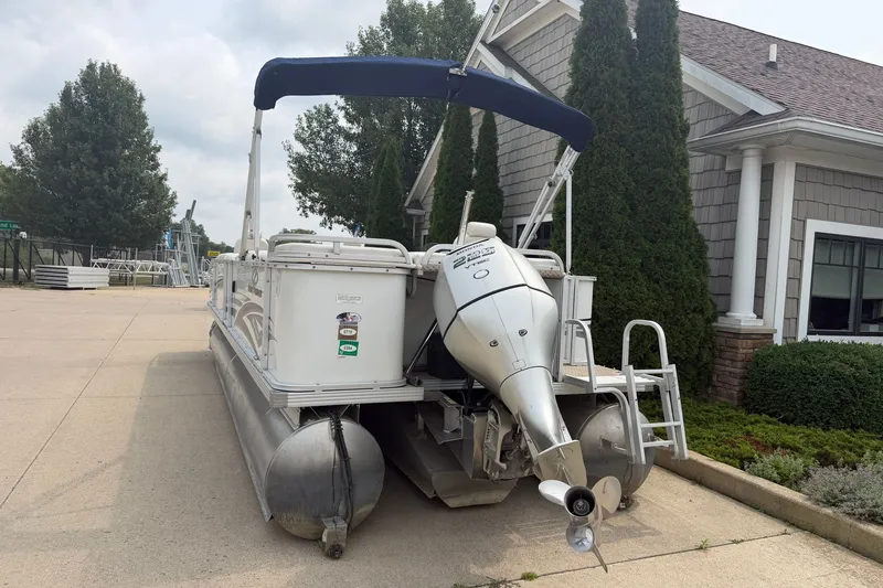 Slide: The Image of 2008 Crest 25 II XRS pontoon boat with outboard motor, parked near a building. - 26