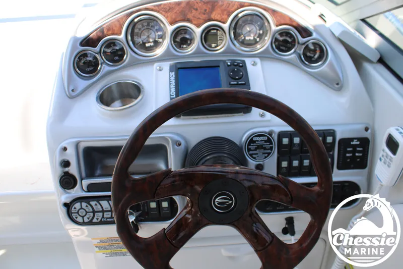 Slide: The Image of The image shows the dashboard of a 2006 Crownline 250 boat with a wood steering wheel and instruments. - 24