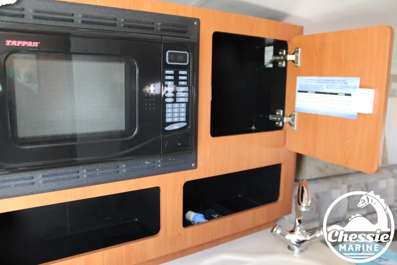 Slide: The Image of A boat's galley with a microwave, open cabinets, and a faucet. - 37