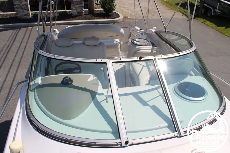Slide: The Image of A 2006 Crownline 250 boat with a spacious cockpit and clear windshield, parked on a trailer. - 27