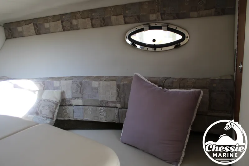 Slide: The Image of Interior of a 2006 Crownline 250 with cushioned seating and a small porthole. - 49