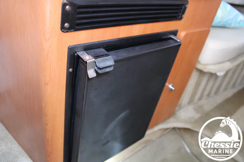 Slide: The Image of A small refrigerator in a boat, surrounded by wood paneling and carpeted flooring. - 38