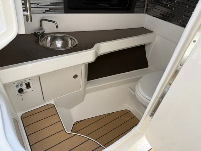 Slide: The Image of The image shows the bathroom of a 2027 Sea Ray SLX 310 with a sink and toilet. - 14