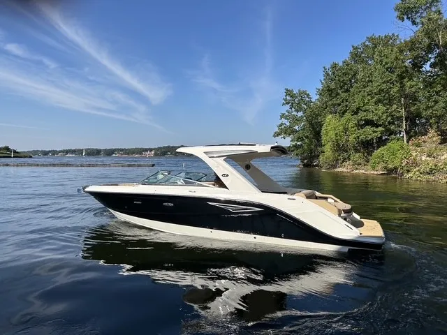 Slide: The Image of A sleek 2027 Sea Ray SLX 310 boat on calm water, surrounded by trees. - 2