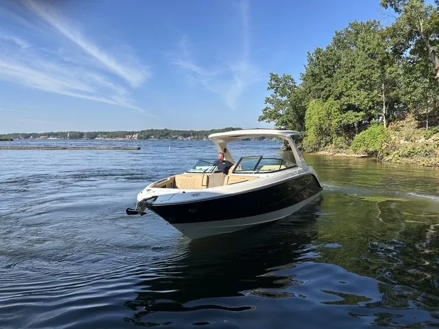 Slide: The Image of A 2027 Sea Ray SLX 310 cruising on a calm lake with a wooded shoreline. - 4