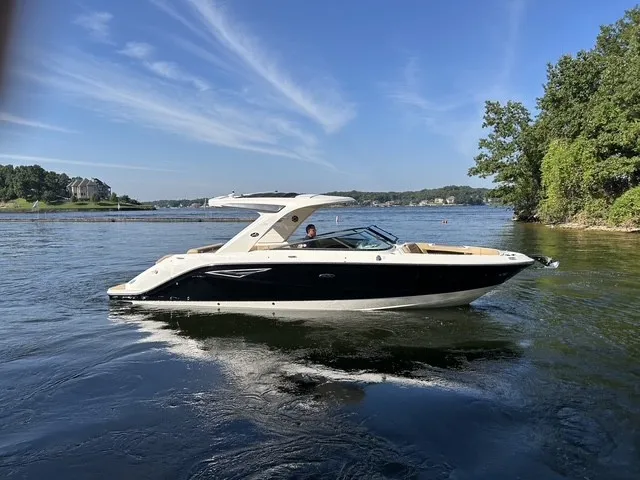 Slide: The Image of A sleek 2027 Sea Ray SLX 310 boat glides on calm water, surrounded by trees. - 6